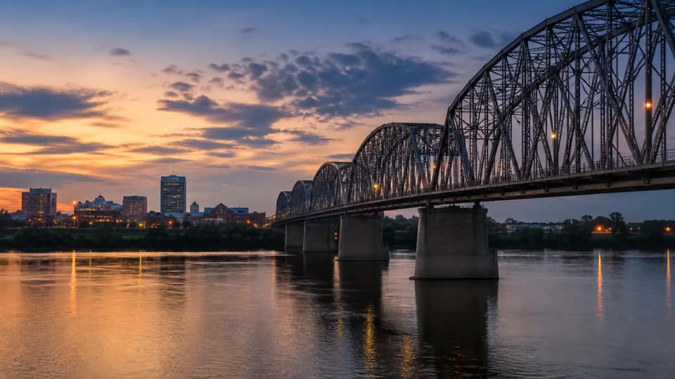 A steel truss bridge over the Missouri River at dusk
